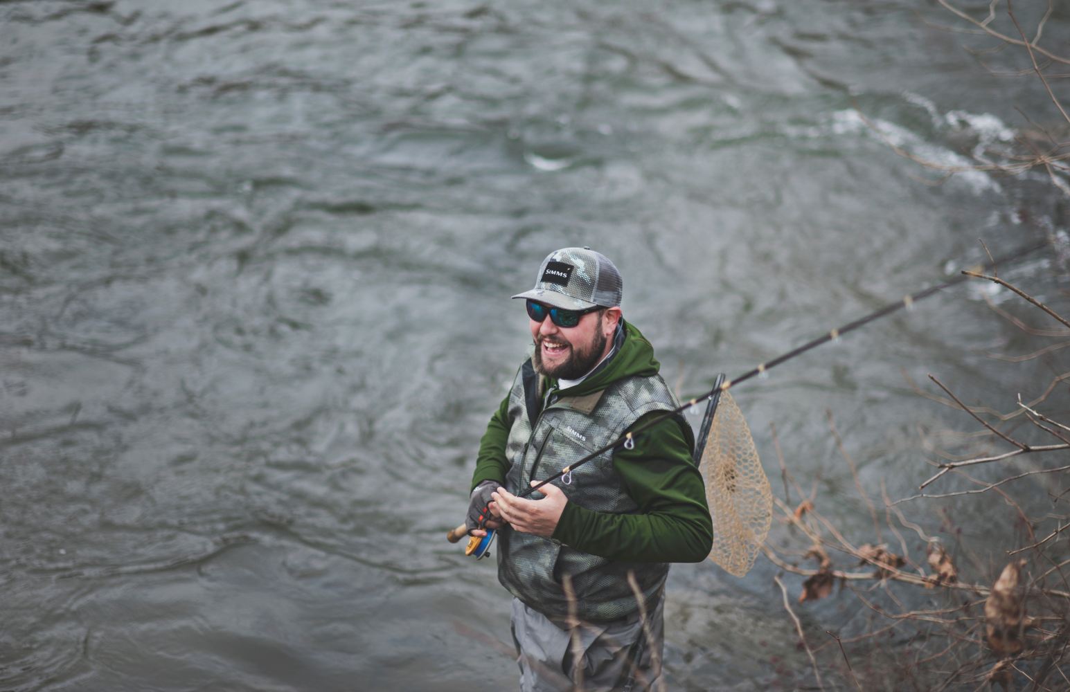 Man smiling and fly fishing on a river