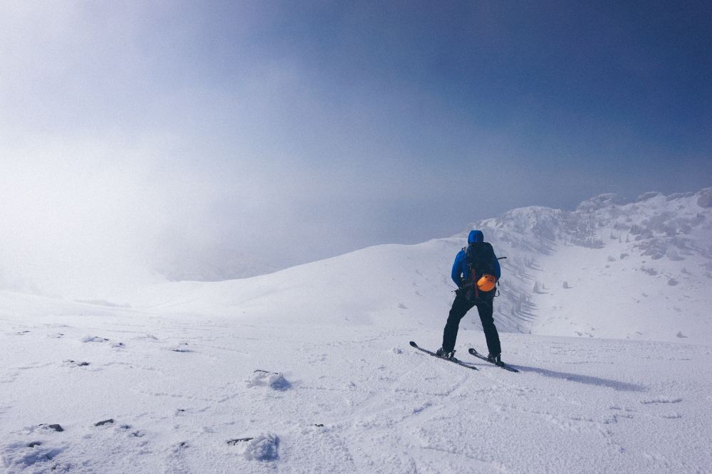 A man looking over a cliff on skiis in a winter landscape