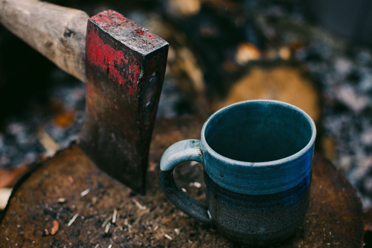 Axe stuck into a log, with a cup of coffee. Camping.