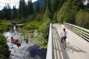 Kid biking over bridge and canoe