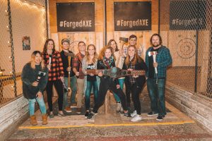 axe throwing group standing in front of targets with a trophy wrestling belt
