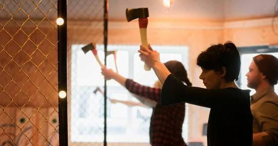 Two people getting ready to throw axes